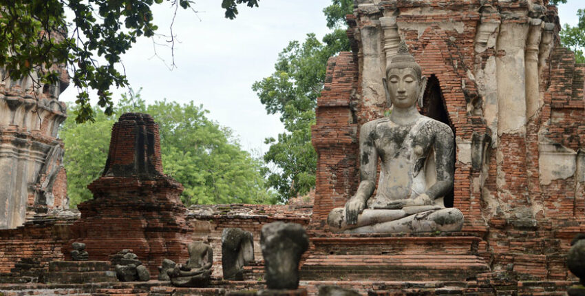 Ancienne statue de Bouddha sur un site historique en ruines de briques.