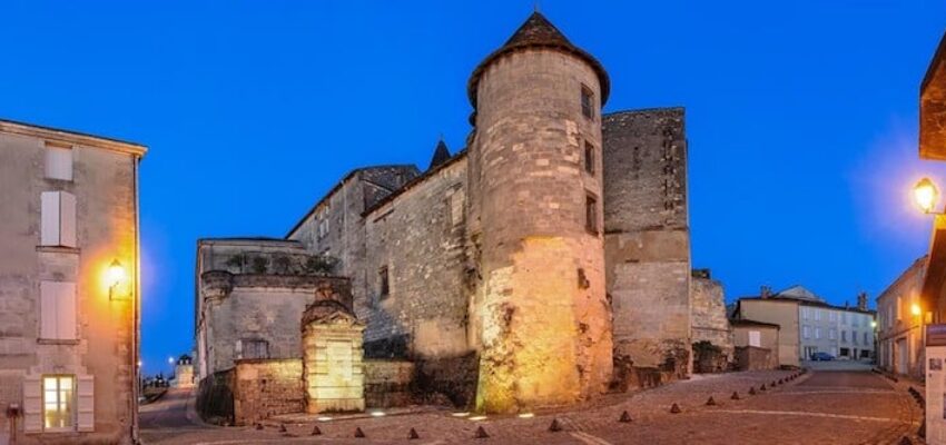 Cognac Châteaubernard fort et tour ronde illuminée au crépuscule.