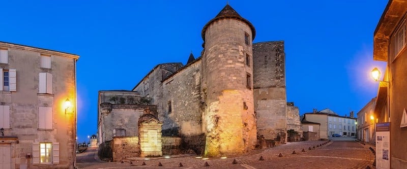 Cognac Châteaubernard fort et tour ronde illuminée au crépuscule.