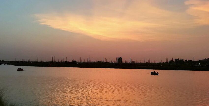 Rivière calme, silhouettes de coucher de soleil, ciel orange-rose.
