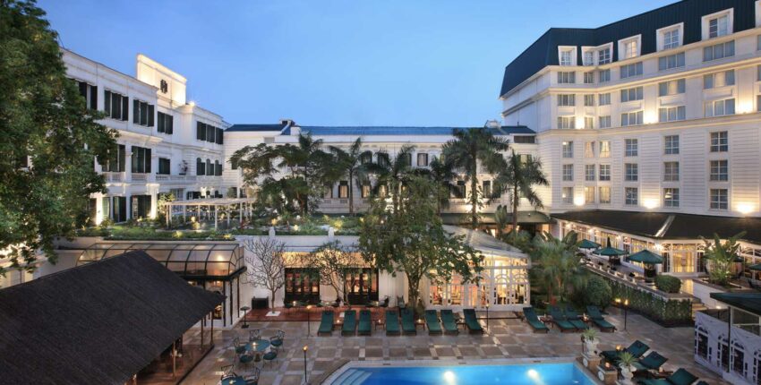 Hôtel luxueux avec piscine et palmiers.