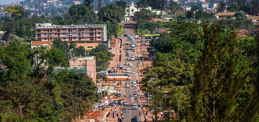 Rue animée de Kampala avec collines et ciel dégagé.