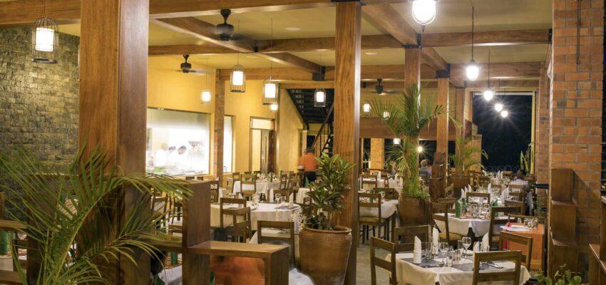 Restaurant spacieux avec poutres et tables bien dressées.