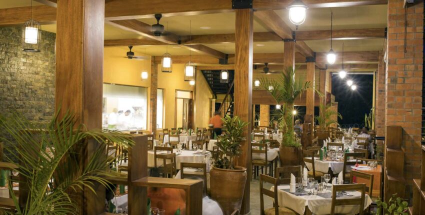 Restaurant spacieux avec poutres et tables bien dressées.