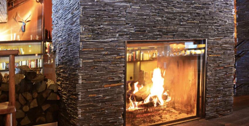 Cheminée en pierre avec feu de bois chaleureux.