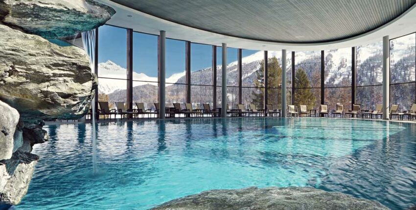 Piscine intérieure avec vue sur montagnes enneigées.