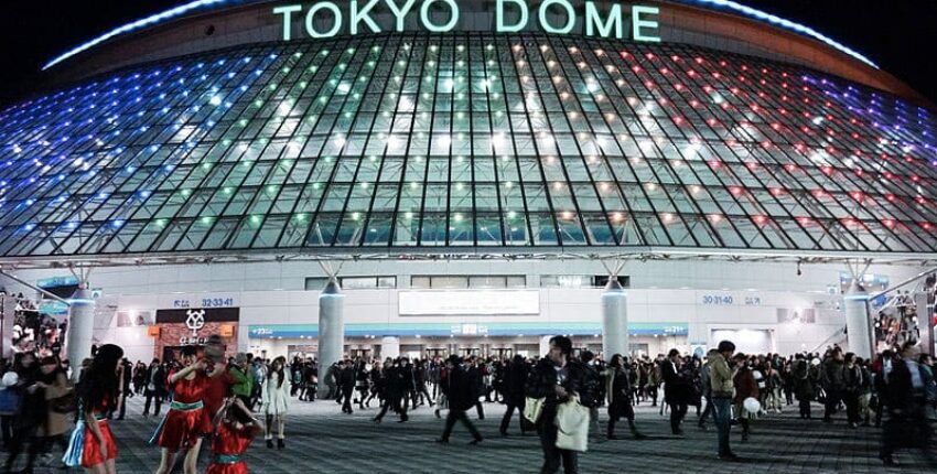 Dôme nocturne illuminé au Tokyo Dome, foule présente.