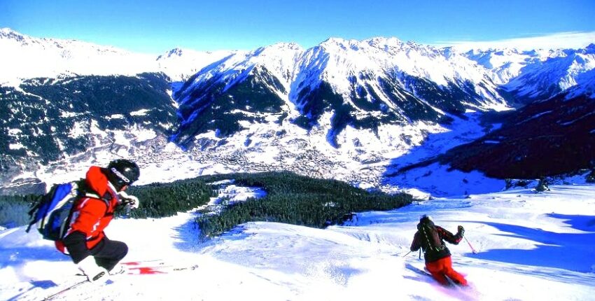 Deux skieurs dévalent une montagne enneigée.